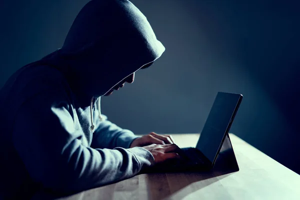 man with the hoodie with computer and he is typing